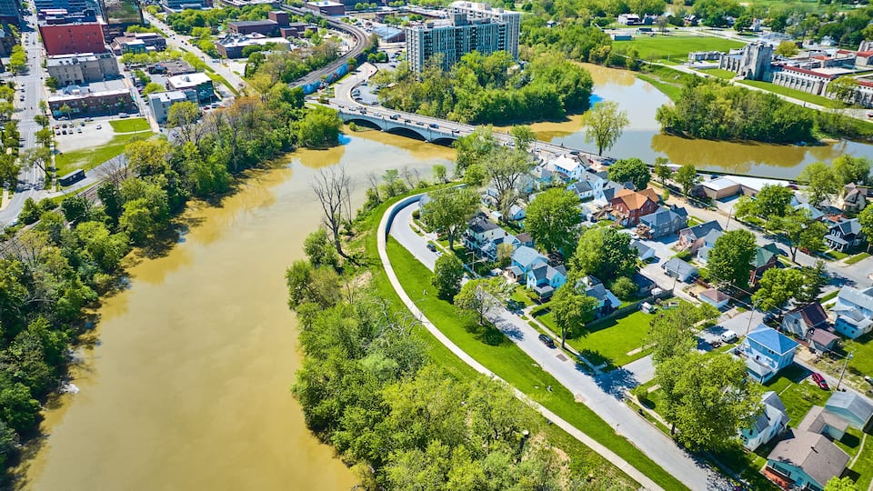A river winding through a residential area with houses and a bridge.