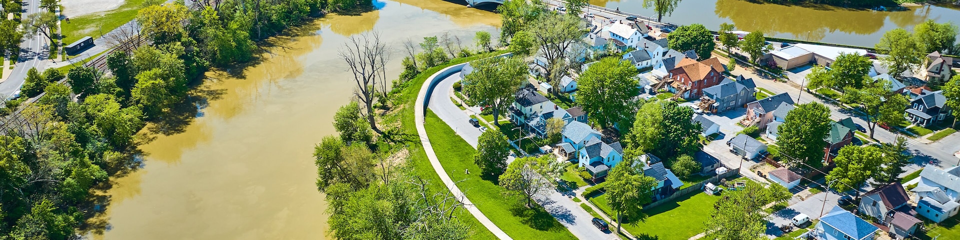 Un río serpenteando por una zona residencial con casas y un puente.