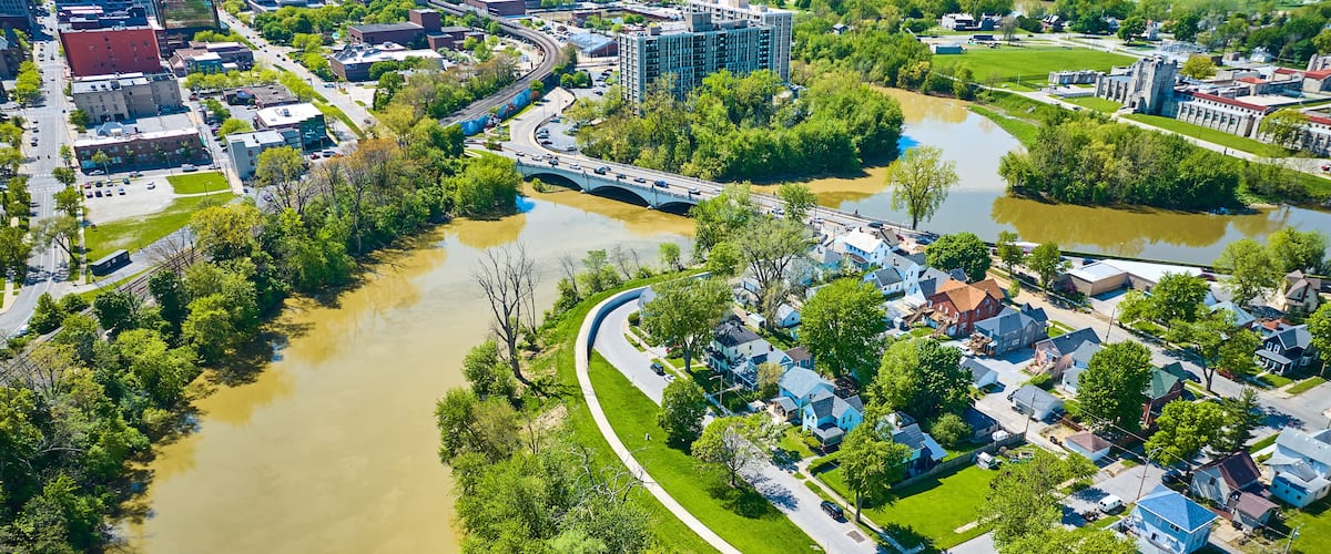 A river winding through a residential area with houses and a bridge.