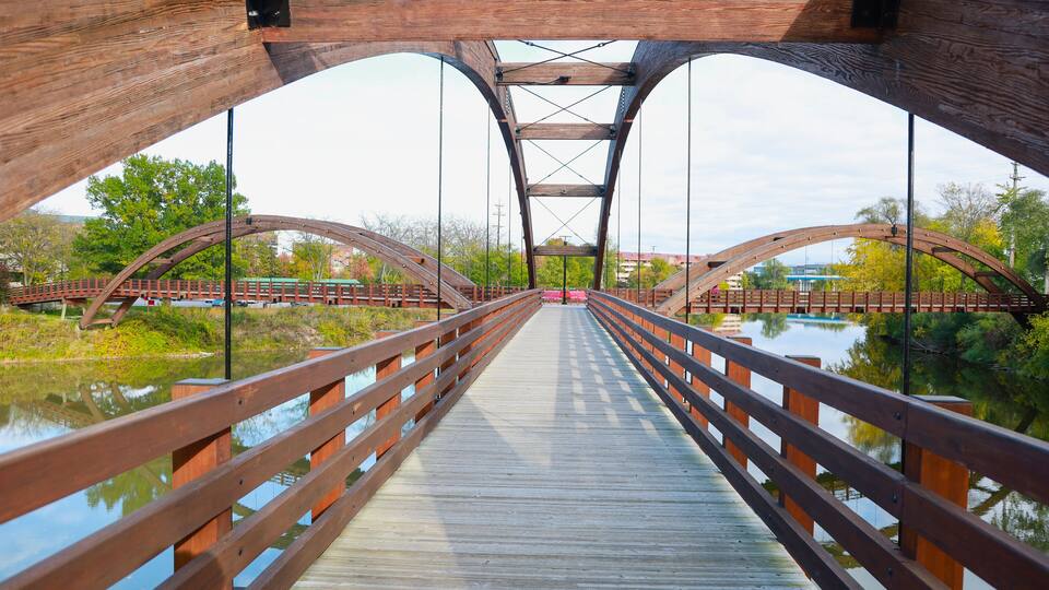 A wooden pedestrian bridge over a calm river with a clear view of the opposite bank.