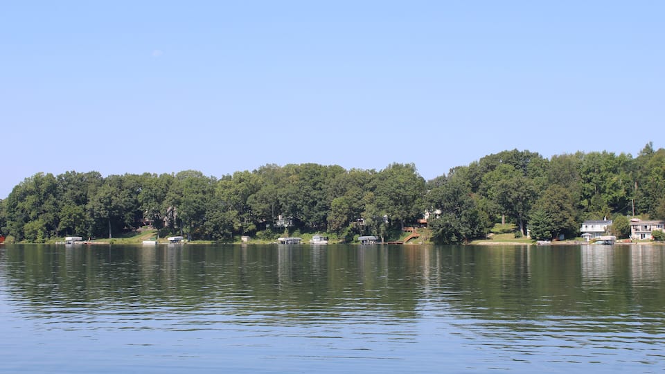 A calm lake with a forested shoreline and several houses.