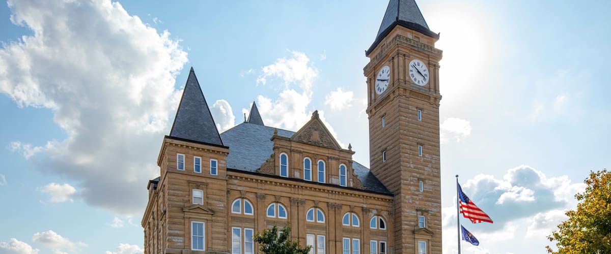 A historic building with a clock tower and a flag.