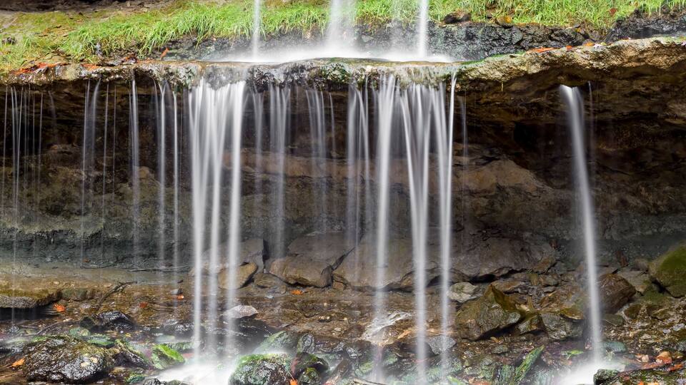 A multi-tiered waterfall surrounded by autumn foliage.