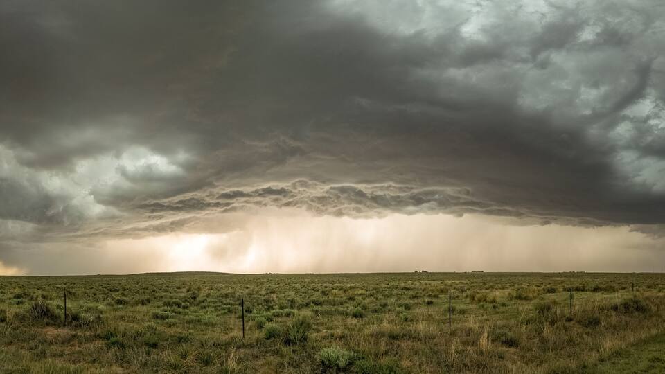 A grassy field with a stormy sky.