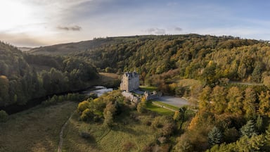 Aerial view of the historic Neidpath Castle standing proudly amidst the autumnal hues of the surrounding forest, where the River Tweed meanders serenely, Peebles, Scotland, United Kingdom.