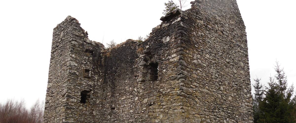 A stone ruin with two towers and a partially intact wall.