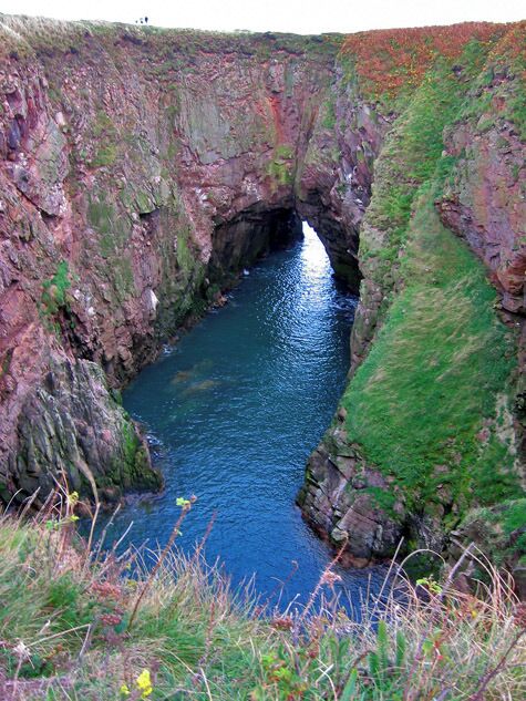 A narrow canyon with a river flowing through it.