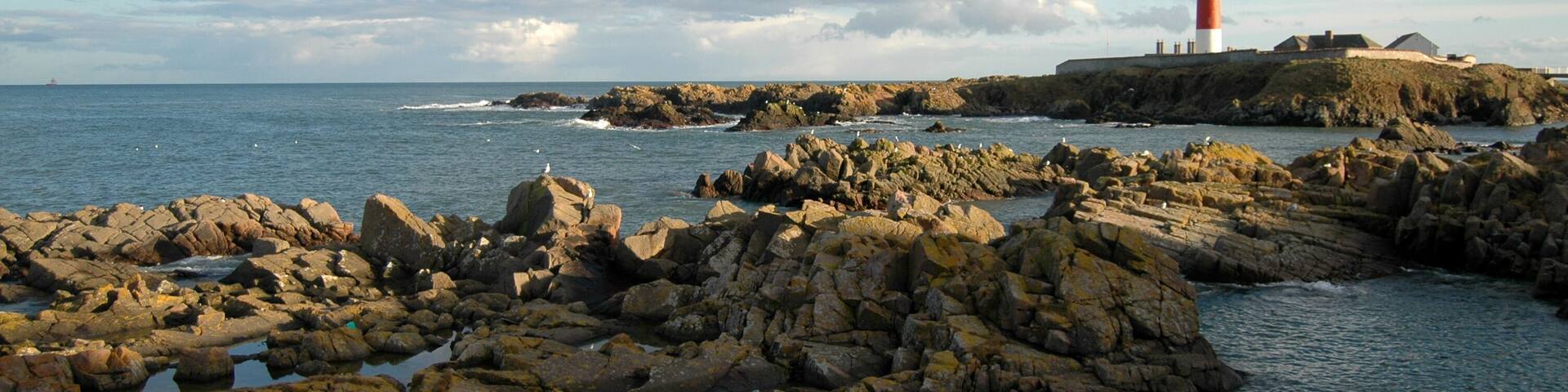 A rocky coastline with a lighthouse on a small island.