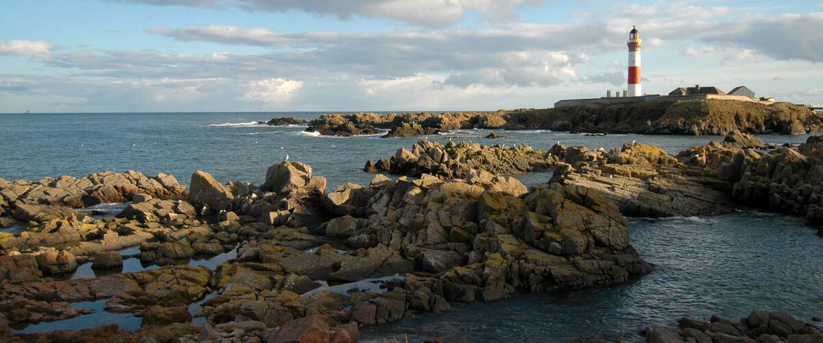 A rocky coastline with a lighthouse on a small island.