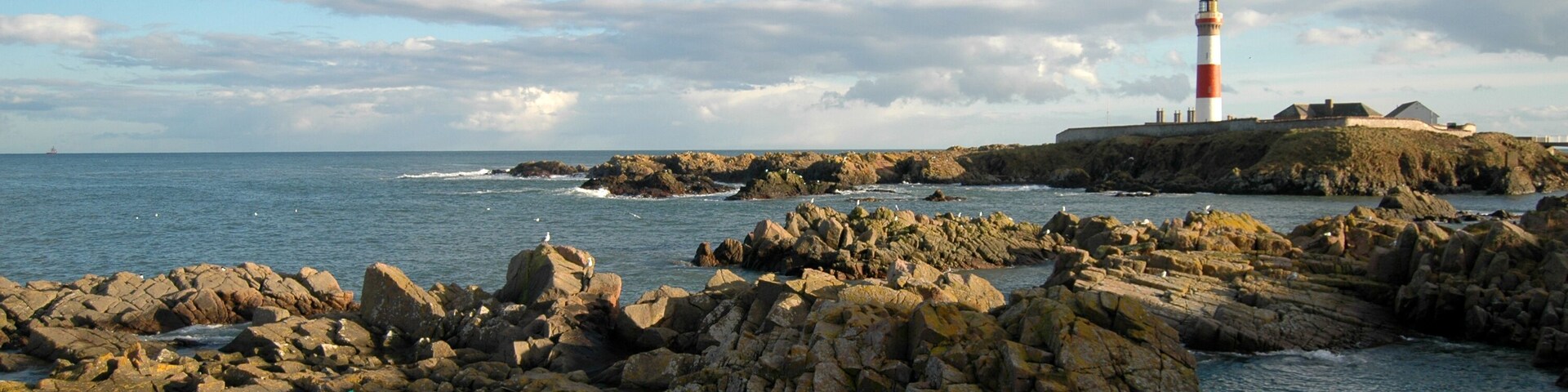 A rocky coastline with a lighthouse on a small island.
