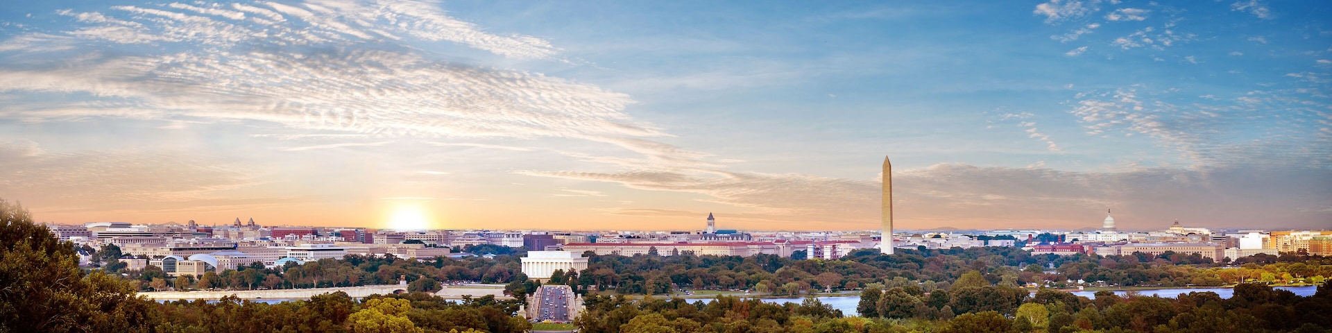 A cityscape with a prominent building in the center, surrounded by trees and a river.