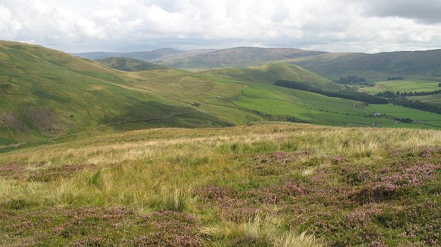 Rolling hills, green fields, and a cloudy sky.