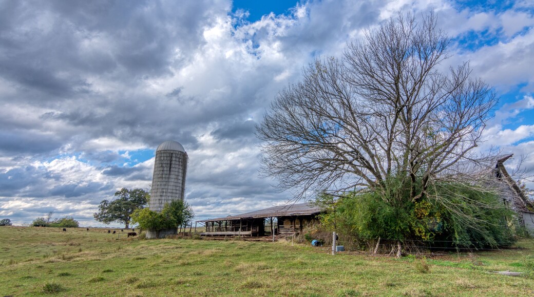 Abandoned barn with silo under stormy clouds