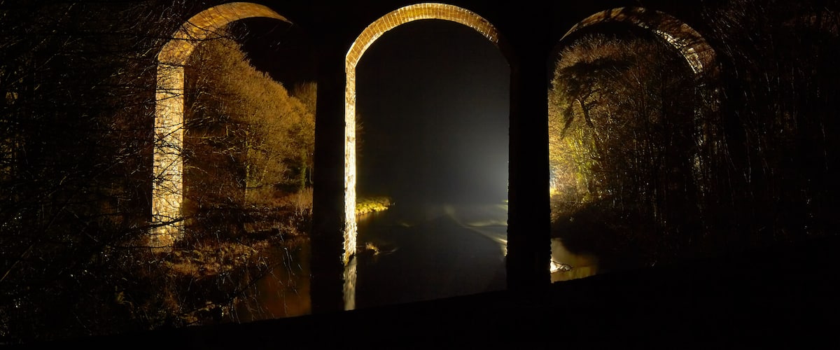A dark, illuminated archway with a misty background.