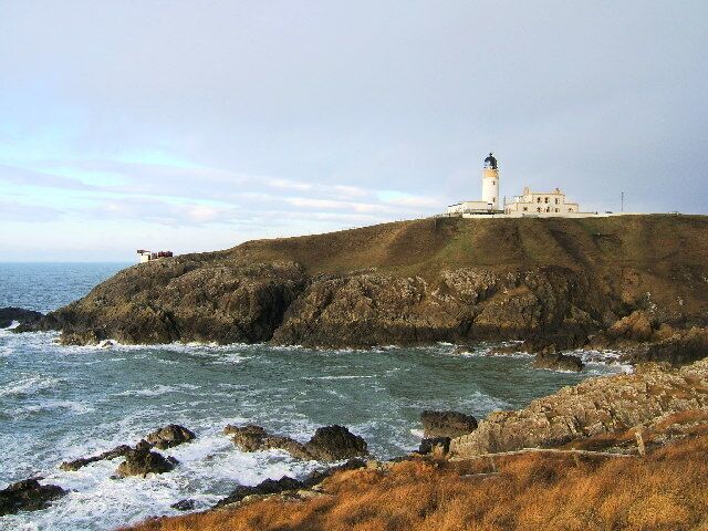 Un faro costero sobre un afloramiento rocoso, con el océano al frente.