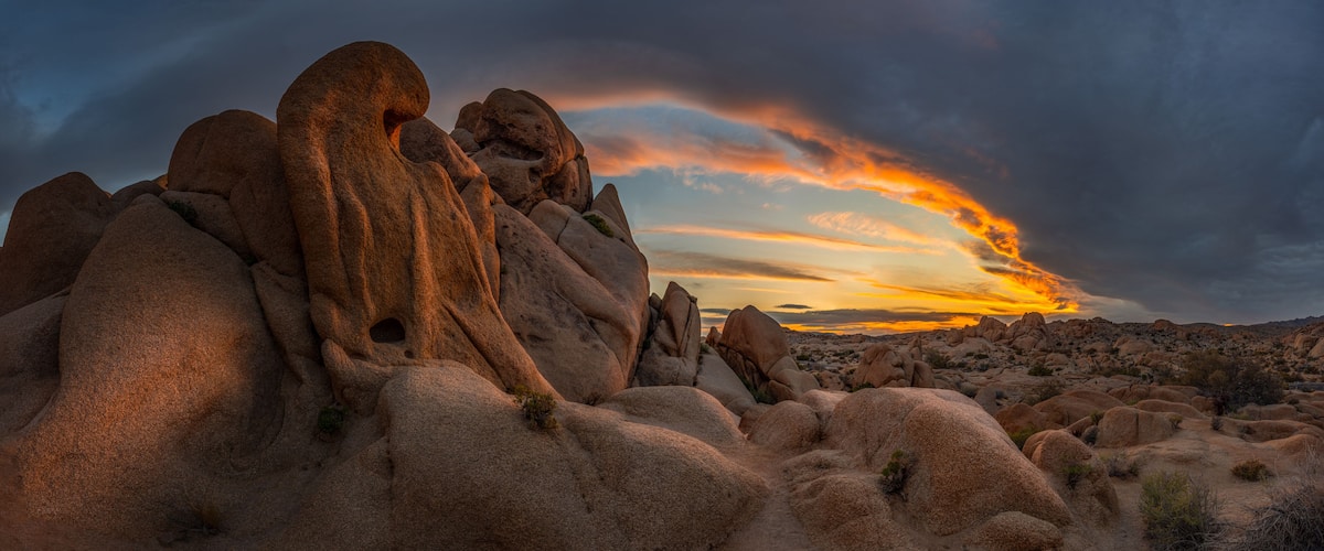 A desert landscape with prominent rock formations during sunset.