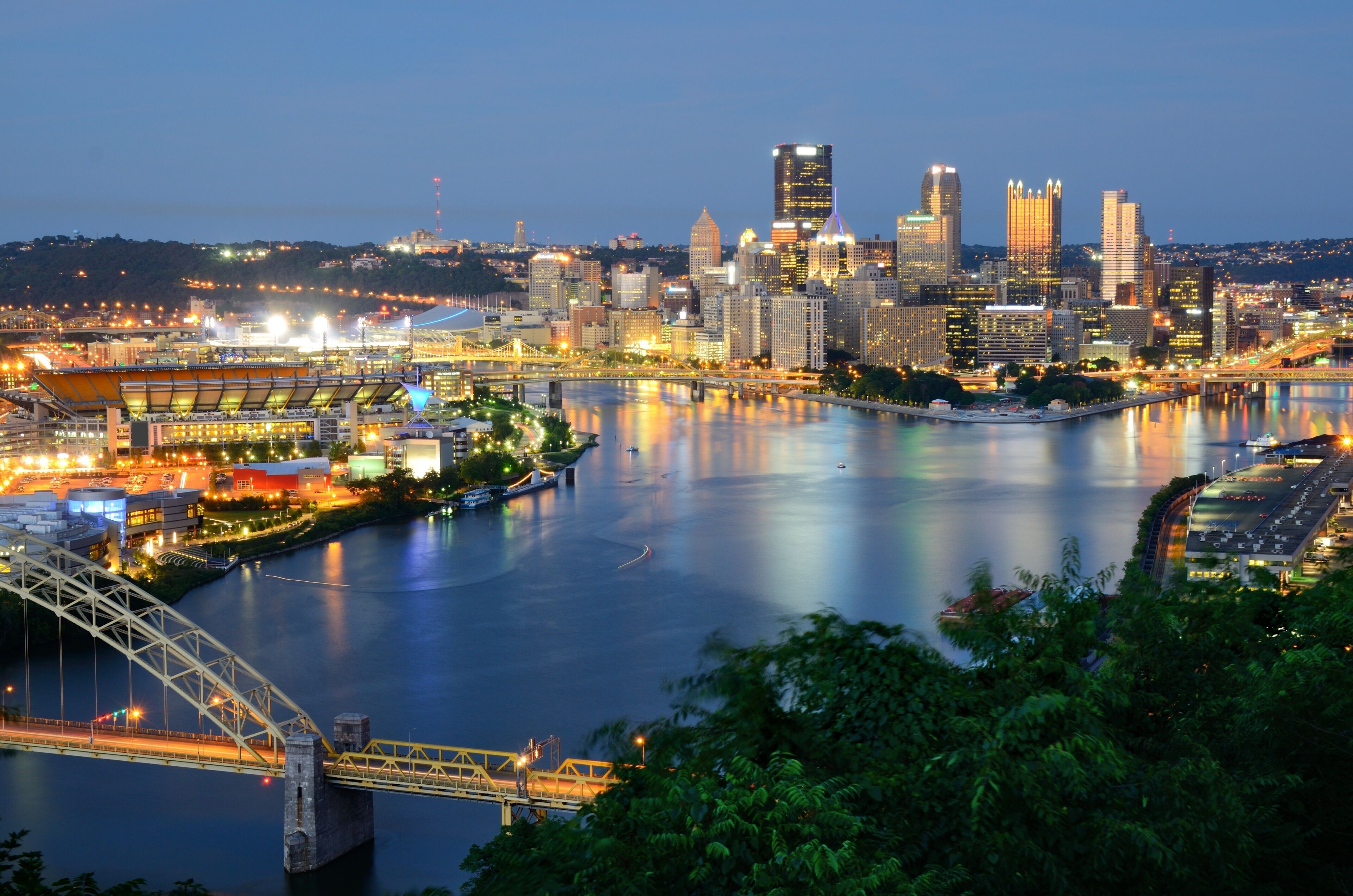 A city skyline with a river, a bridge, and a stadium.