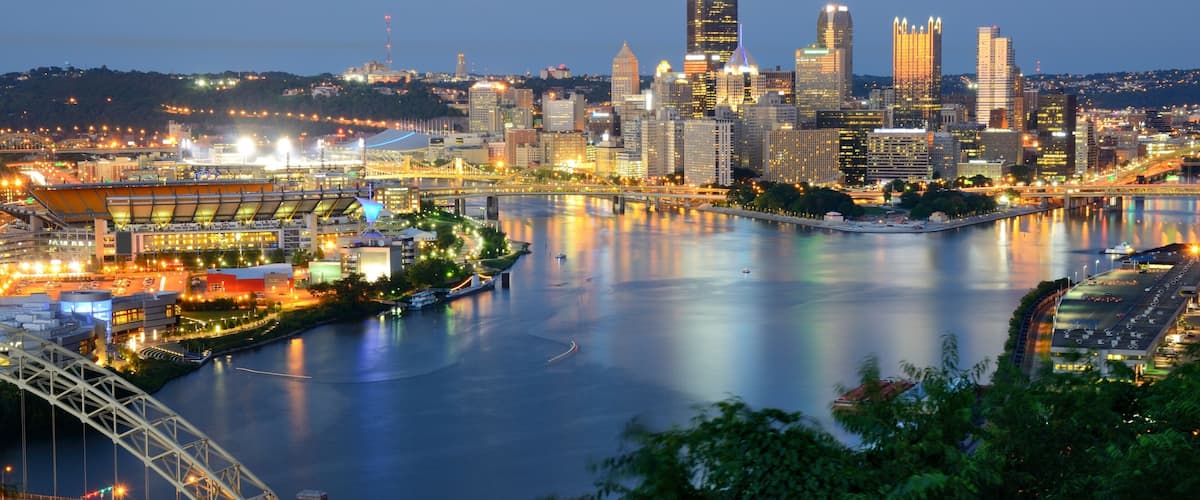 A city skyline with a river, a bridge, and a stadium.