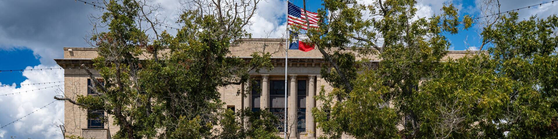 A historic building with a flagpole, a statue, and a red bench.