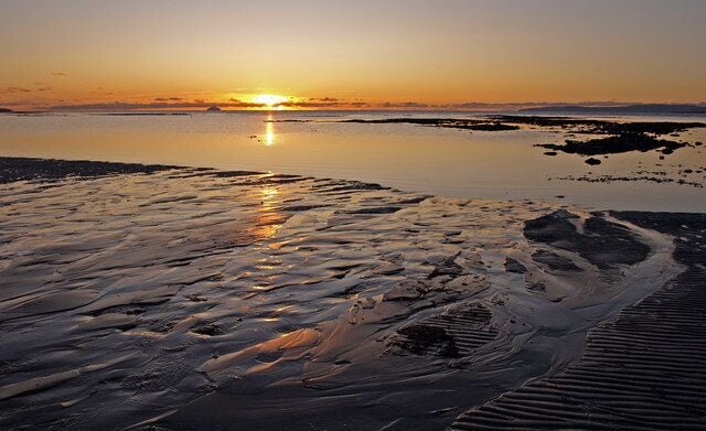 Black Rocks, Troon Sunset on the Firth of Clyde with Ailsa Craig on the horizon to left of sun.
