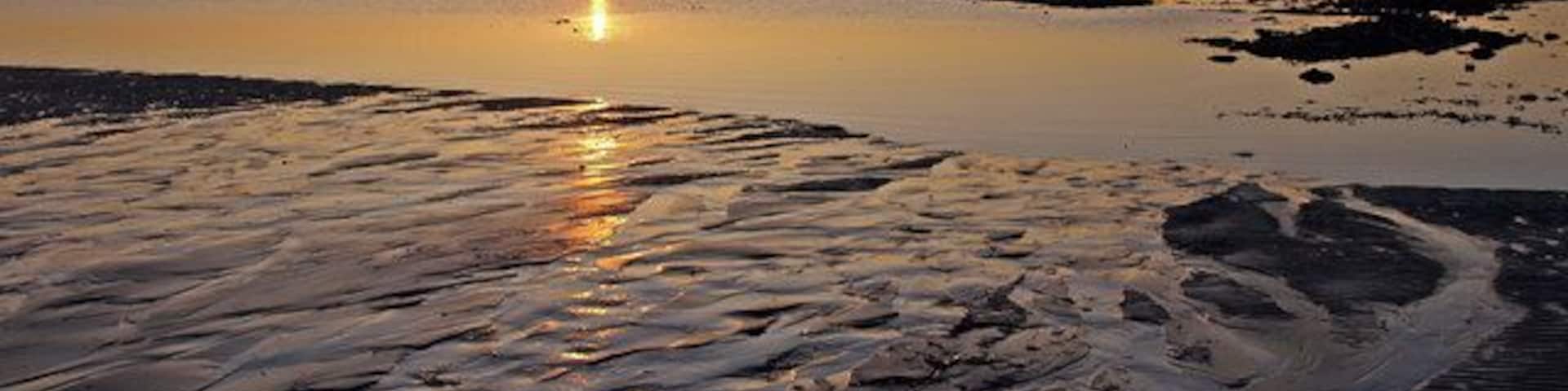 Black Rocks, Troon Sunset on the Firth of Clyde with Ailsa Craig on the horizon to left of sun.