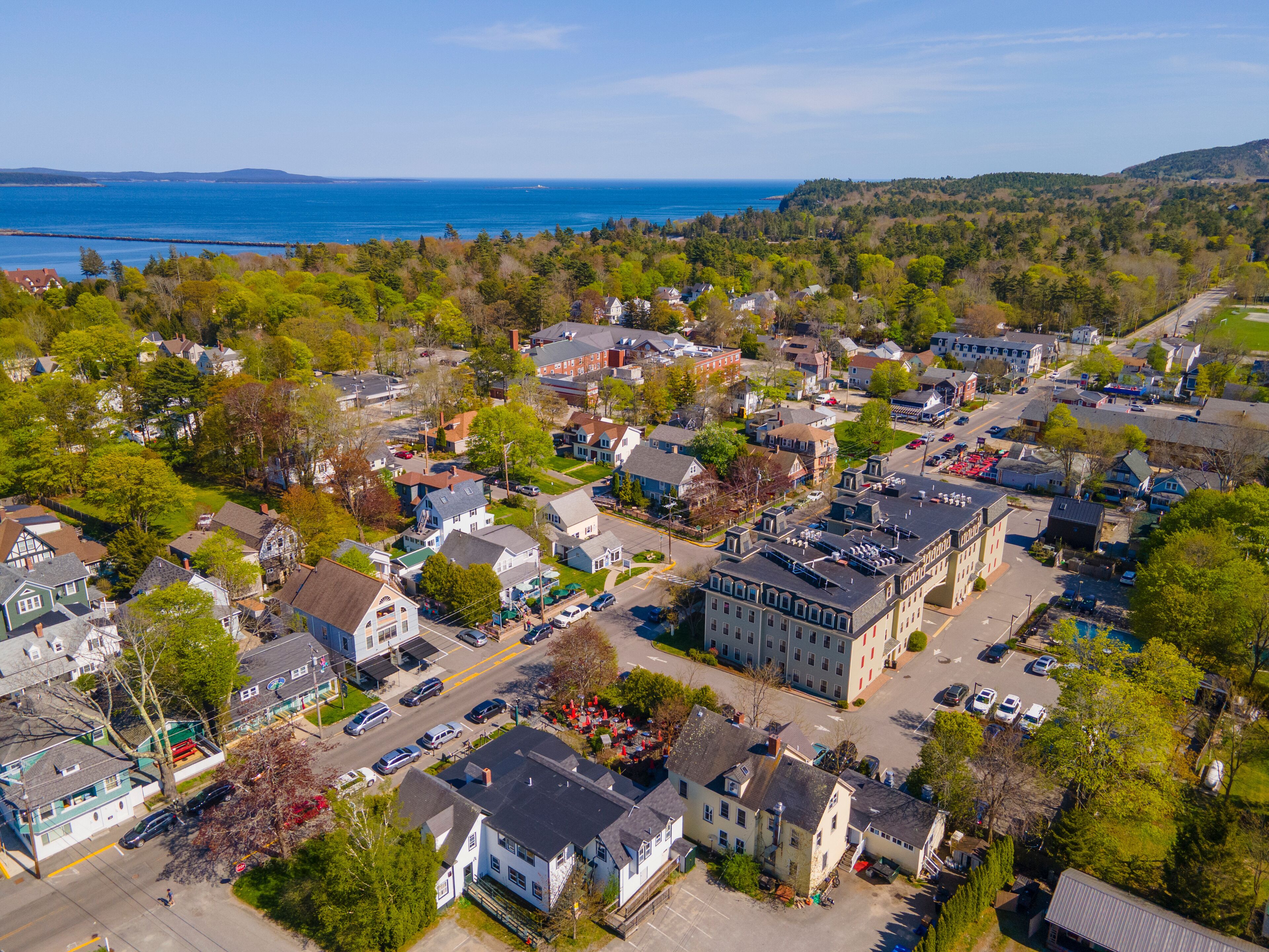 A coastal town with a mix of residential houses and commercial buildings, surrounded by greenery and a view of the sea.
