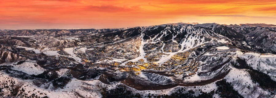 Un paysage montagneux avec une ville nichée dans une vallée, entourée de sommets enneigés.