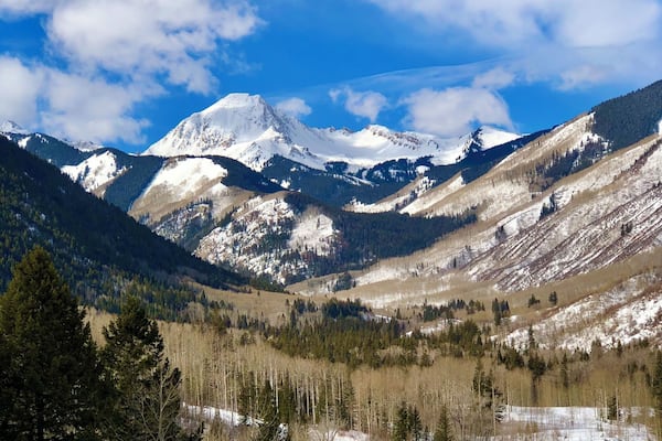 A mountainous landscape with snow-covered peaks and a valley with sparse trees.
