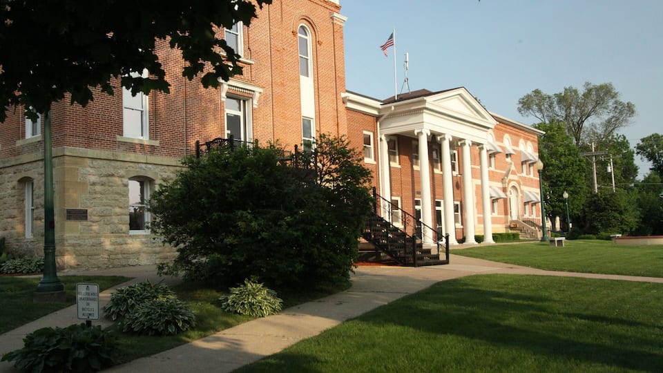 A historic brick building with columns and a flagpole.