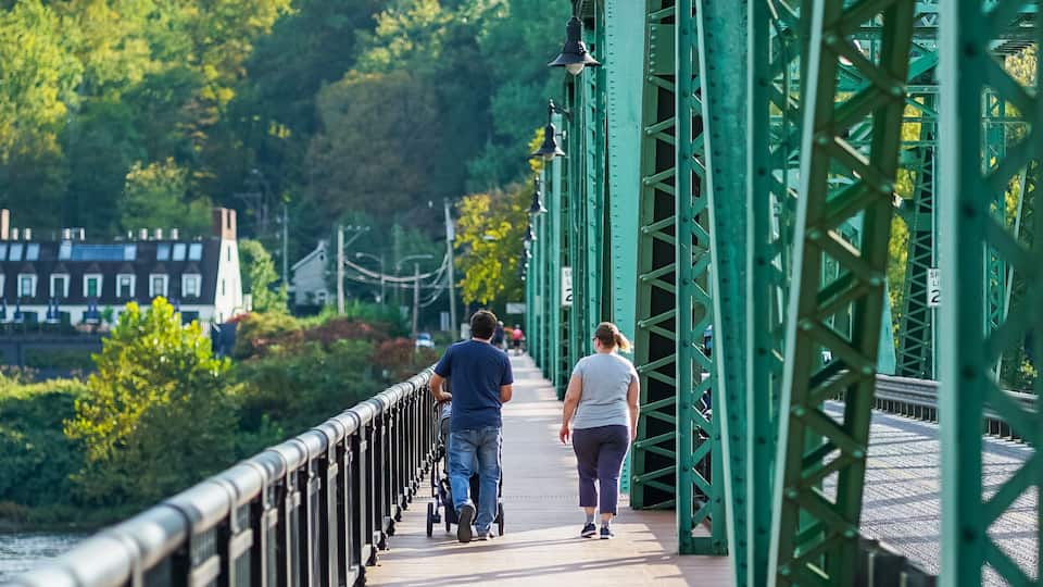 A pedestrian bridge with green metal railings and a wooden walkway.