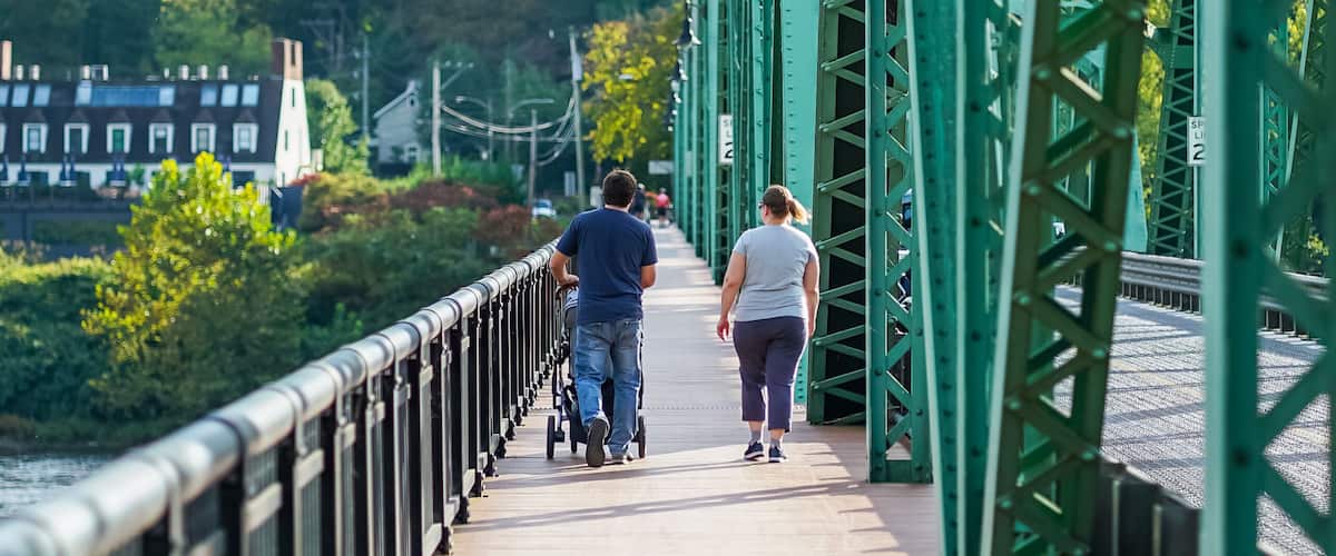 A pedestrian bridge with green metal railings and a wooden walkway.