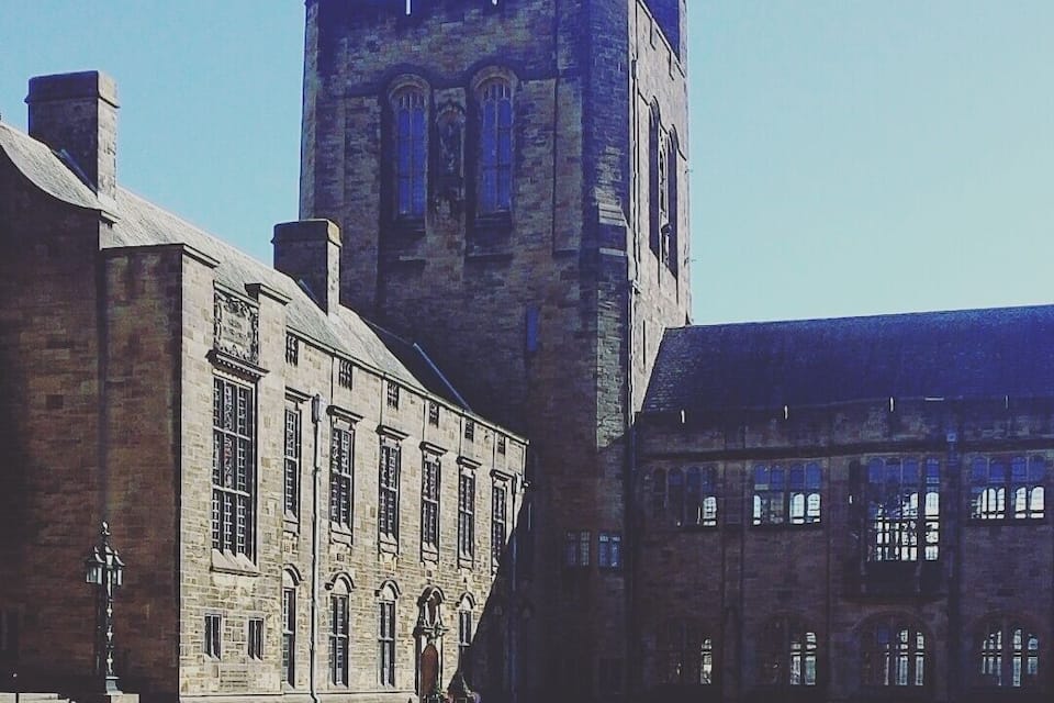 Un edificio histórico con una torre destacada y un patio con mesa de picnic.
