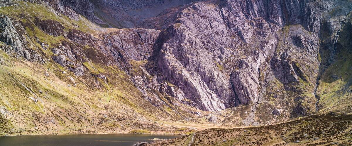 A mountainous landscape with a lake and a winding road.