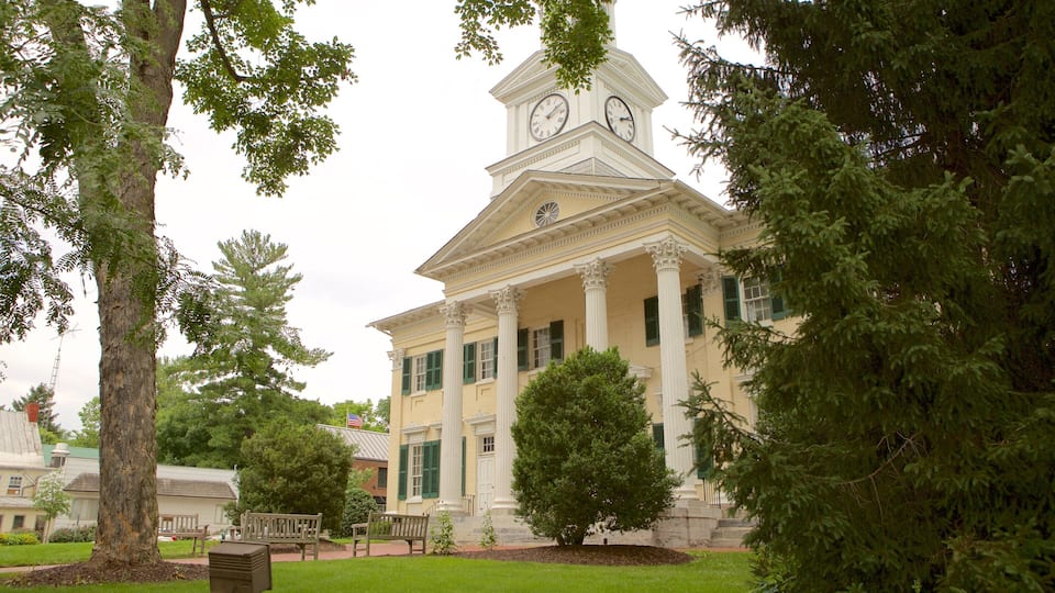 A historic building with a clock tower, surrounded by trees and a well-maintained lawn.