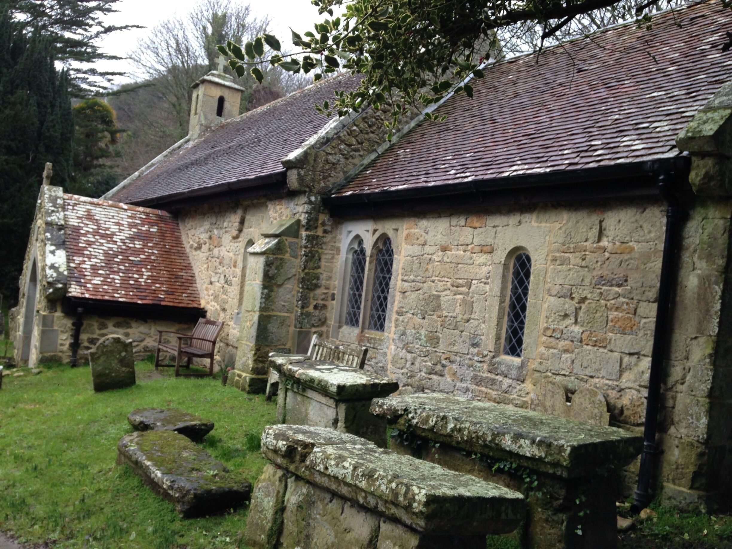 An old stone church with a tiled roof, arched windows, and a small bell tower.