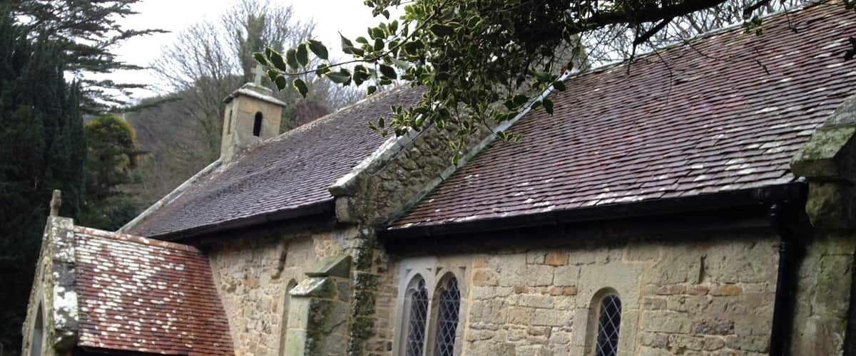 An old stone church with a tiled roof, arched windows, and a small bell tower.