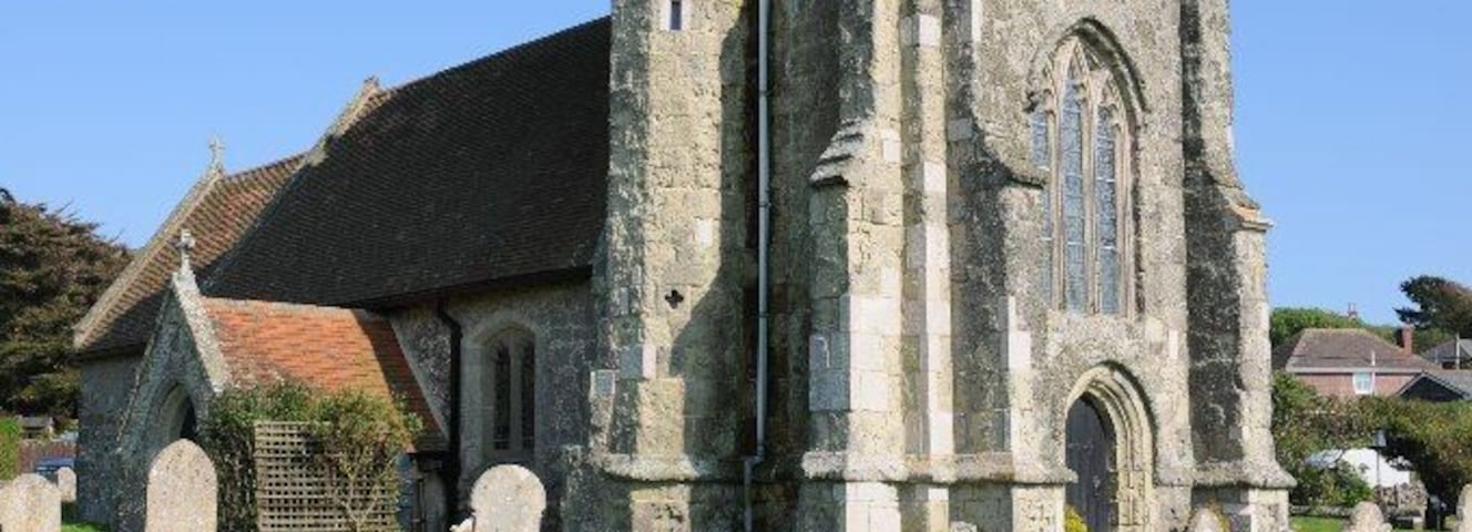 Una iglesia histórica con una torre alta y un cementerio al frente.