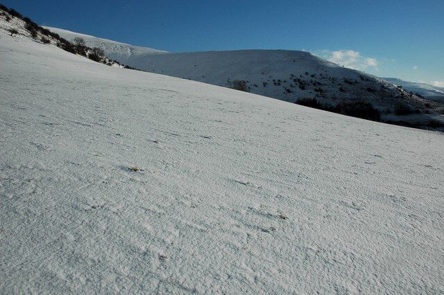 Encosta de montanha coberta de neve sob um céu claro.