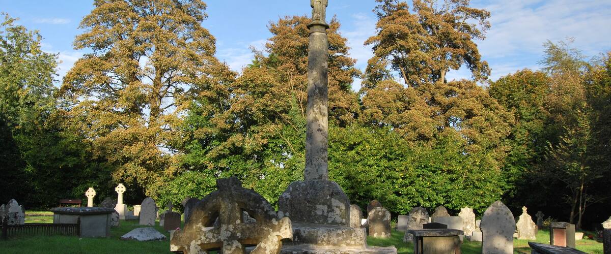 A cemetery with gravestones and a prominent cross monument.