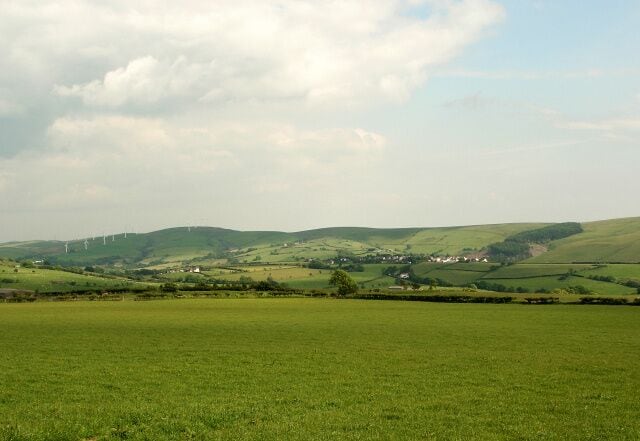 A view over farmland towards Cwm Ogwr Fach A view from a point at the southern edge of Ogmore Forest. The whites of buildings at Glynogwr (SS9587) can be made out in the right half of the picture. Mynydd Maendy and some of the turbines of its wind farm (chiefly ones in SS9786) are seen towards the left of the photograph.