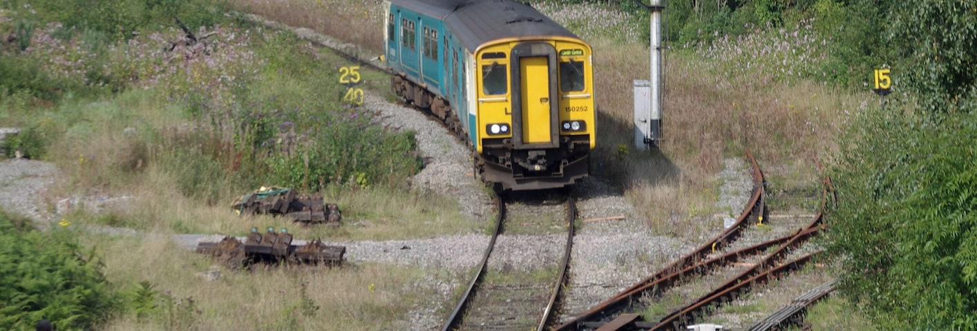 Arriva Trains Wales 150252 approaches the signalbox at Tondu, where the signaller is waiting to exchange line tokens.