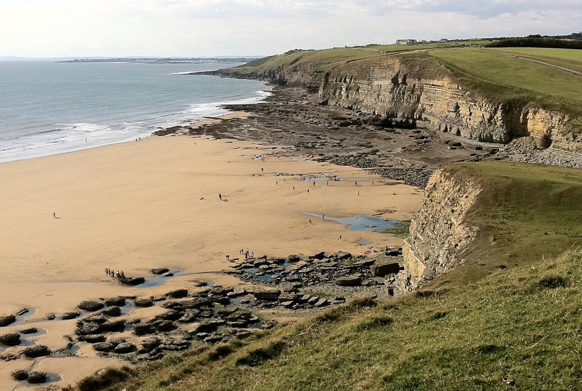 A coastal beach with cliffs and a sandy shore.