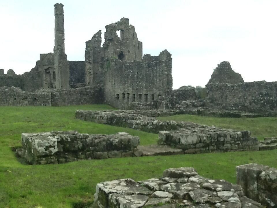 Ruinas antiguas con muros de piedra y una torre alta y erosionada.