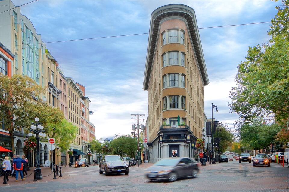 Calle con edificios históricos, un edificio en esquina curva y automóviles.