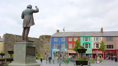 A statue of a man in a coat, a colorful building, and a stone wall in the background.