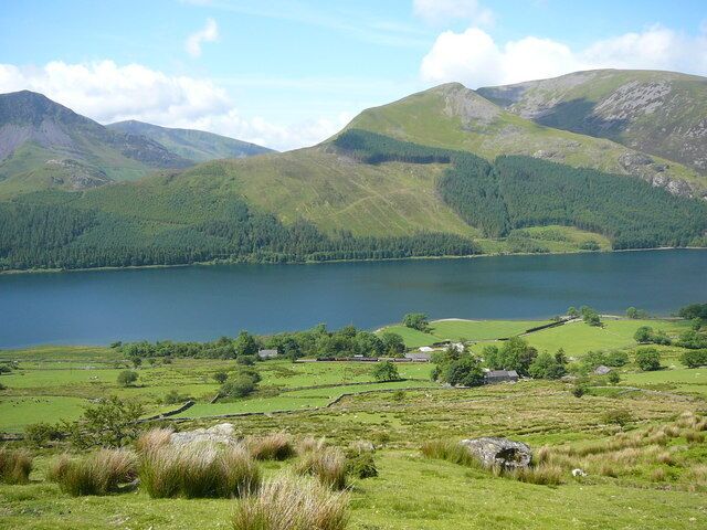 A lake surrounded by green hills and scattered trees.