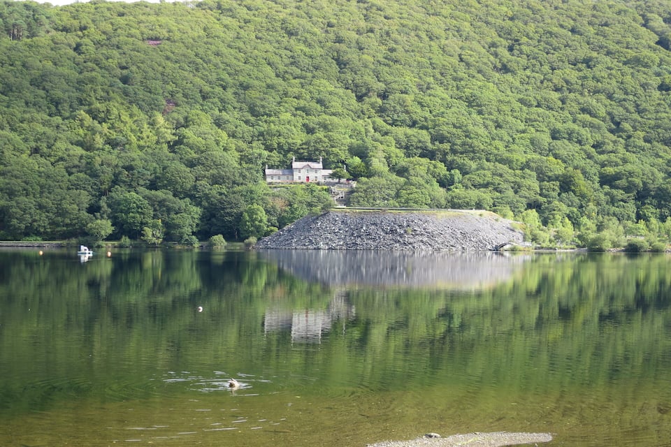 A lake with a house on a hill and a small boat.
