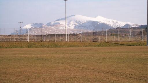 The Sports Field at Ysgol Brynrefail This is a field with a view. The snow covered peaks of Crib Goch, Carnedd Ugain and Yr Wyddfa (Snowdon) form the background.