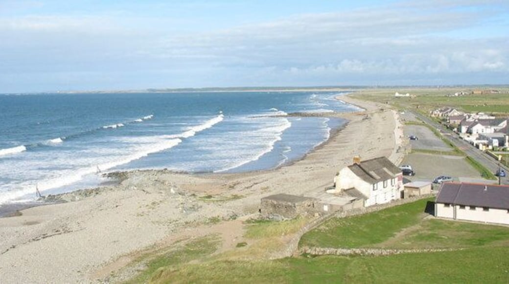Dinas Dinlle Village from Dinas Dinlle Dinas Dinlle Village is dominated by Dinas Dinlle - an Iron Age fort. This view is taken from the ramparts of that fort. It shows the beach, which has gained the Blue Flag Award, and which consists of pebbles at the top and fine sand lower down (here hidden by the high tide). It is a popular venue for wind surfing. There are several cafes and shops in the village.