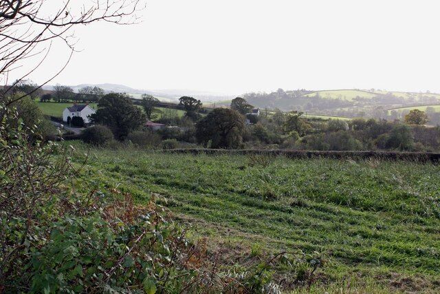 A rural landscape with rolling hills, a white building, and a stone wall.